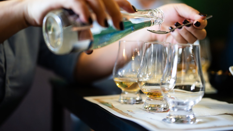 Person adding water in single malt whisky glass.