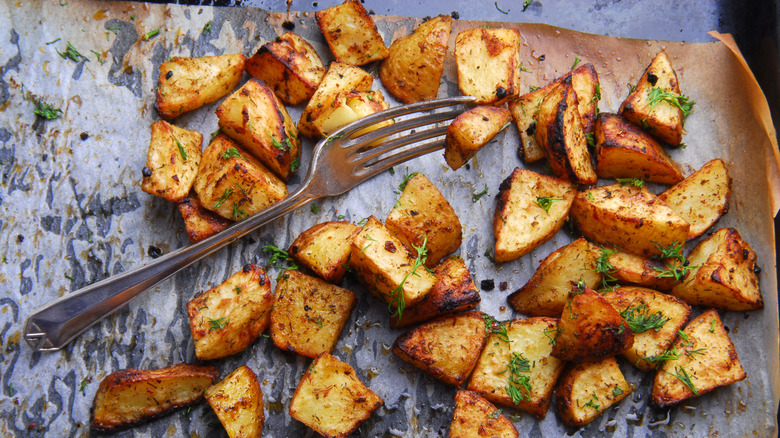 Roasted potatoes on wax paper, one pierced by a fork