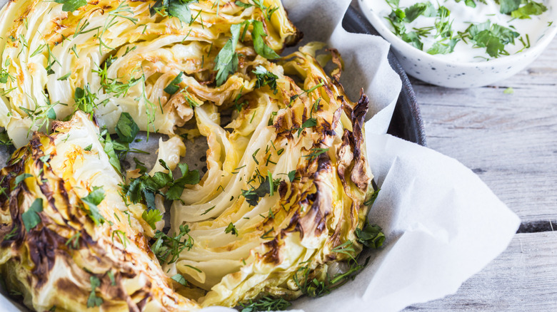 Roasted cabbage wedges in a dish on a wooden table.