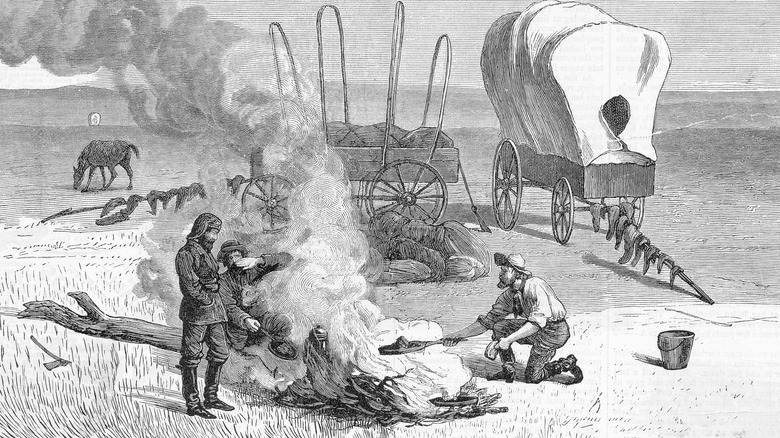 Old print of cowboys cooking over an open fire on the Oregon Trail.