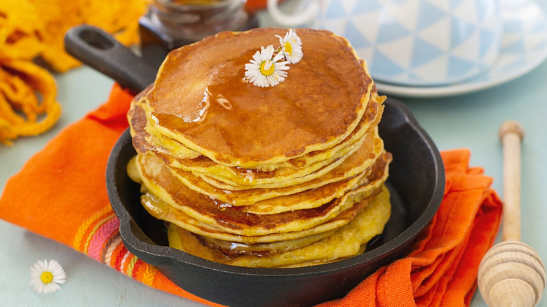 A stack of johnnycakes drizzled with honey.