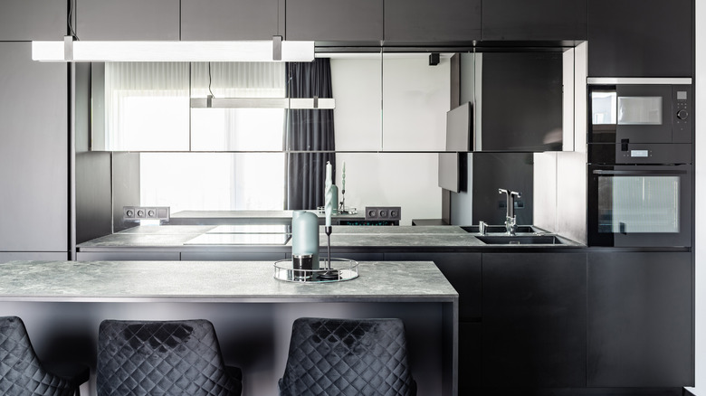 a modern kitchen with gray countertops and mirrored cabinets