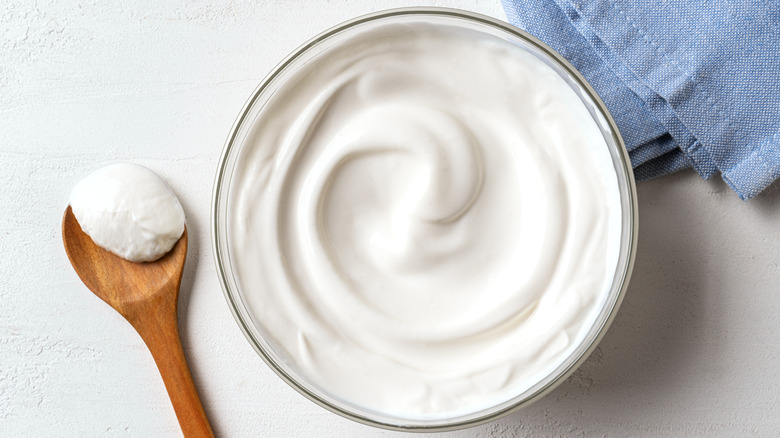 A bowl of thick cream and a wooden spoon on the side