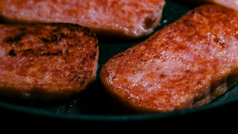 Frying slices of Spam in a skillet.