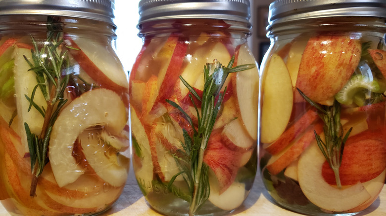 three jars of pickled aples with sprigs of rosemary