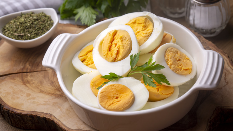 hard boiled eggs in a white ceramic dish, peeled and sliced