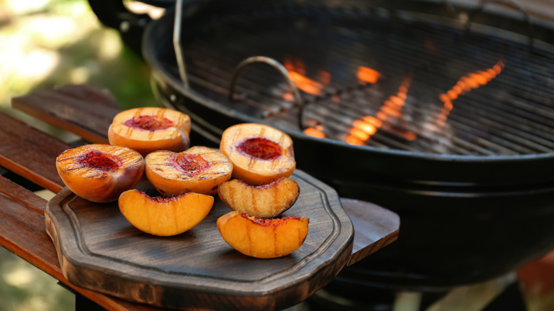 Grilled peaches on a wooden board.