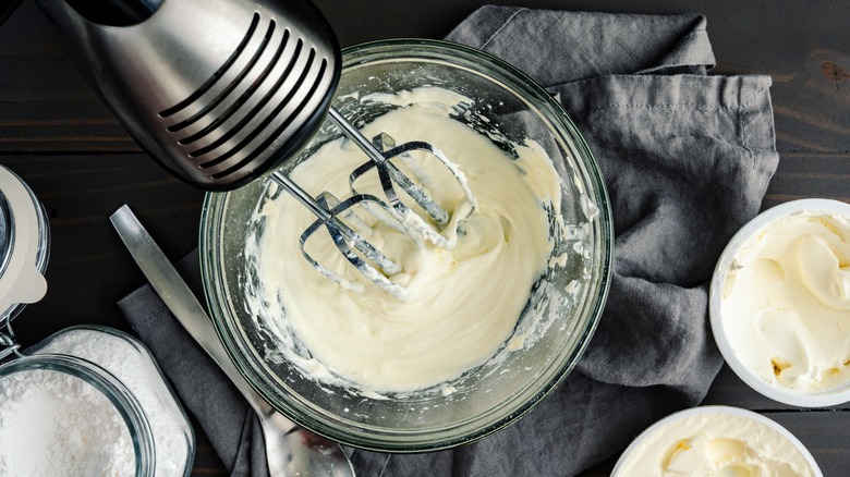 A wooden bowl of mascarpone on a cutting board.