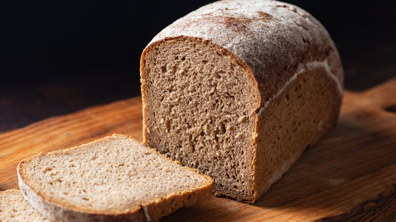 A sliced loaf of rye bread on a wooden board.