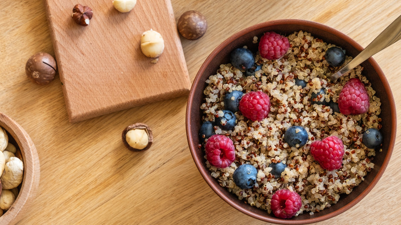 bowl of quinoa with berries and nuts on the wooden table
