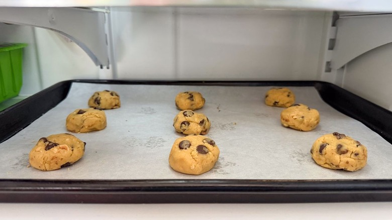 Raw Nutella-stuffed chocolate chip cookie dough on parchment-lined baking sheet in freezer