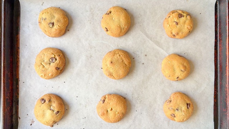 Baked Nutella-stuffed chocolate chip cookies on parchment-lined baking sheet