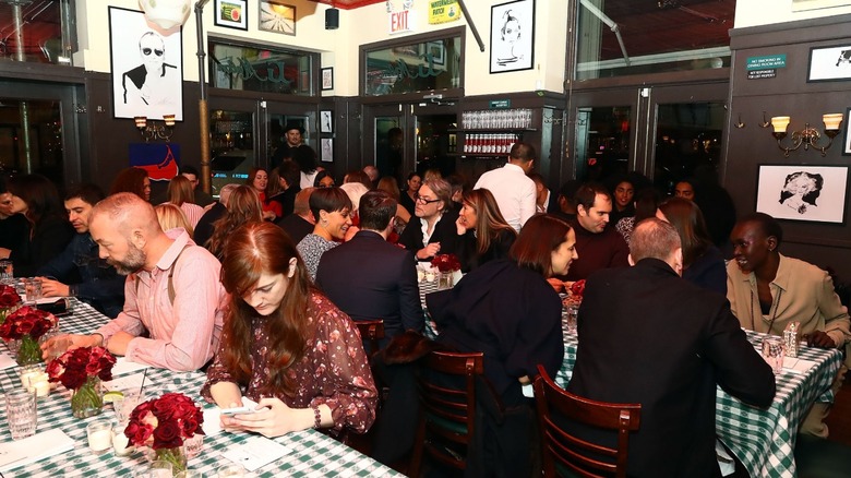 Diners sitting at tables with gingham tablecloths inside at J.G. Melon in New York City