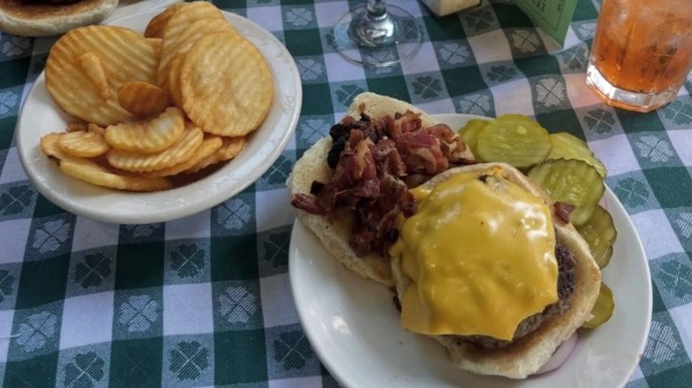 A meal at J.G. Melon in New York City with a cheeseburger and pickles on one plate and fries on another