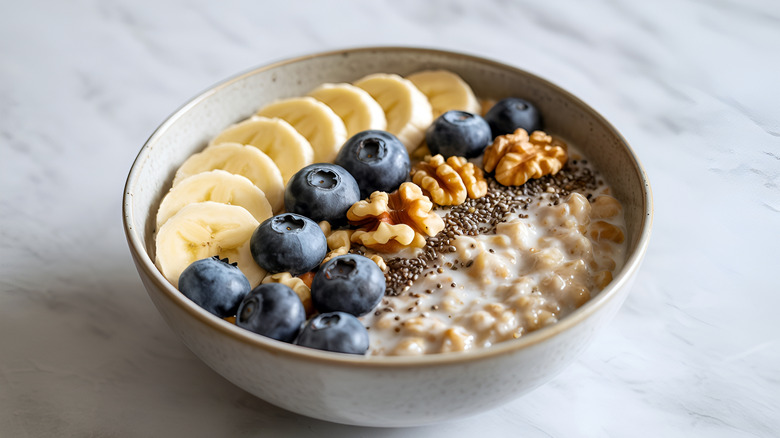 Bowl of oatmeal topped with bananas, blueberries, walnuts, and chia seeds