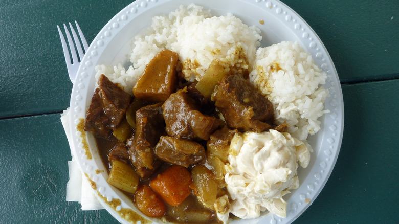 A Hawaiian plate lunch with scoops of rice and macaroni salad, and a portion of beef stew.