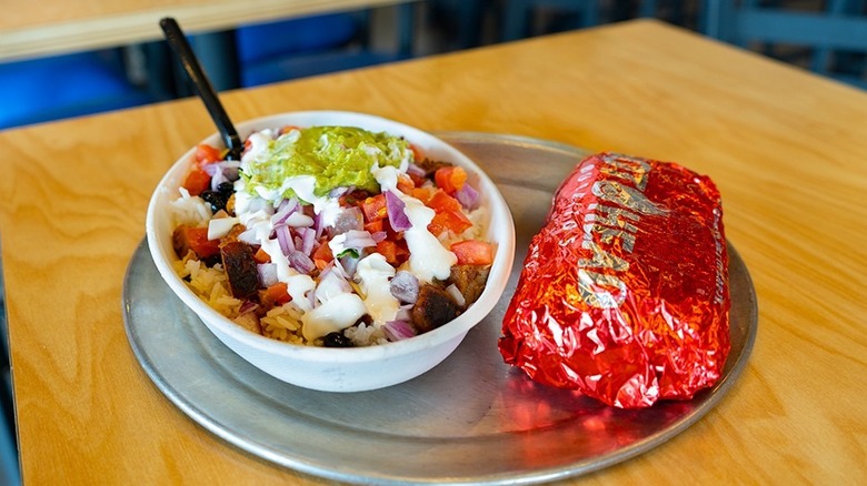 Burrito bowl next to a wrapped burrito on a silver tray