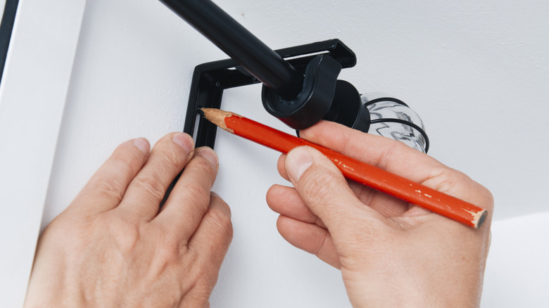 person marking where to install a curtain rod