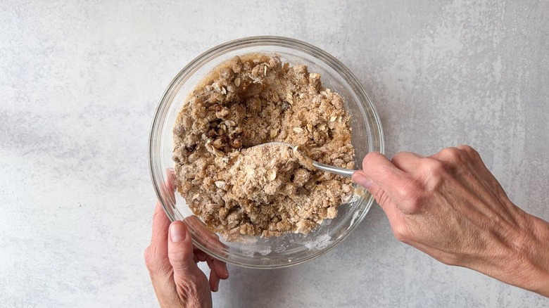 Mixing blueberry crumb cake topping in glass bowl with fork