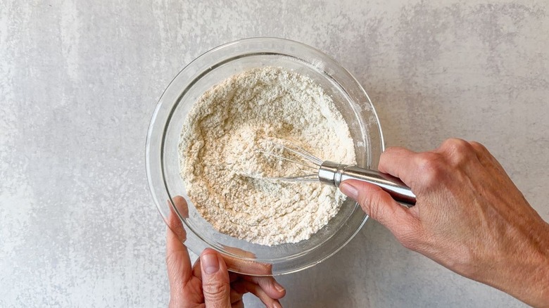 Mixing blueberry crumb cake dry ingredients in glass bowl with whisk