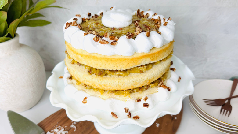Layered lane cake topped with pecans on cake stand