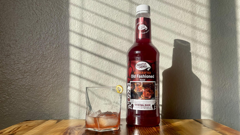 Bottle of Master of Mixes Handcrafted Old Fashioned Mixer with a cocktail made