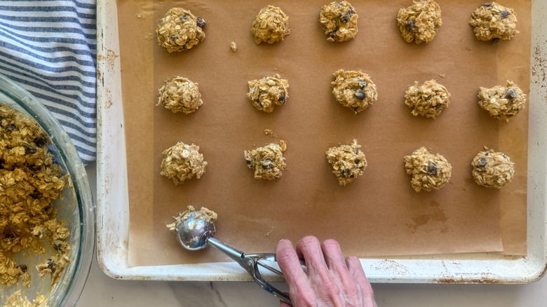 hand adding dough to baking sheet