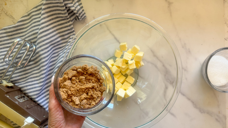 hand adding brown sugar to bowl