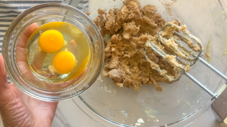 hand adding eggs to bowl