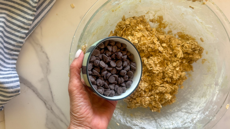 hand adding chocolate chips to bowl