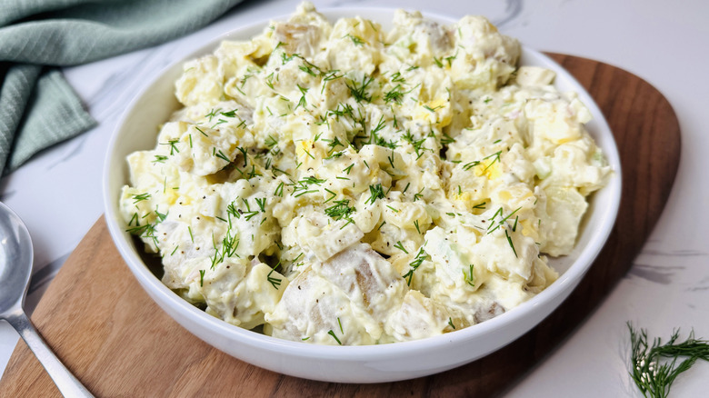 Potato salad in bowl garnished with dill