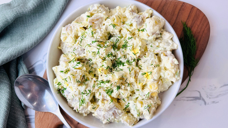 Potato salad garnished with dill in bowl