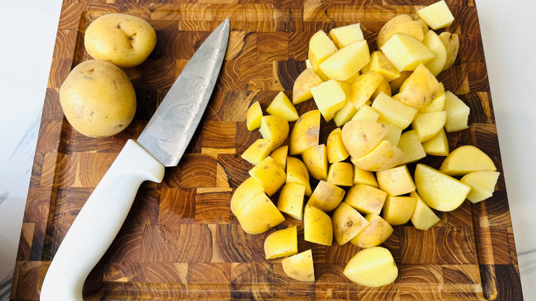 Chopped potatoes and knife on wooden board