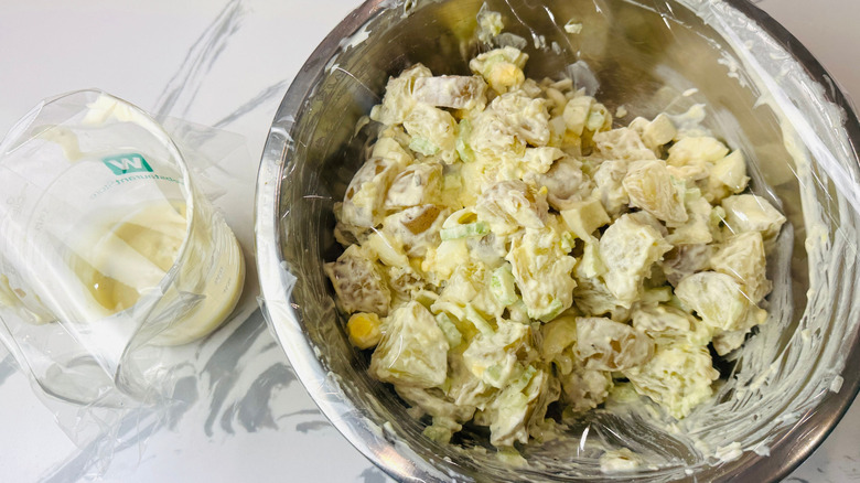 Potato salad in bowl covered with plastic wrap