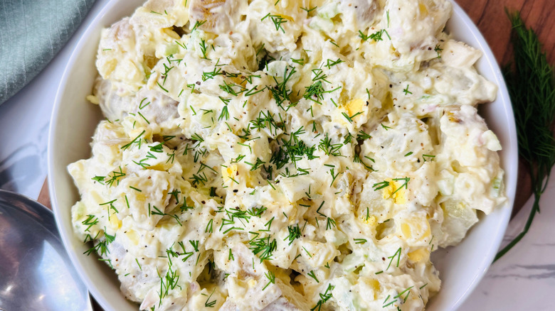 Potato salad in bowl garnished with dill