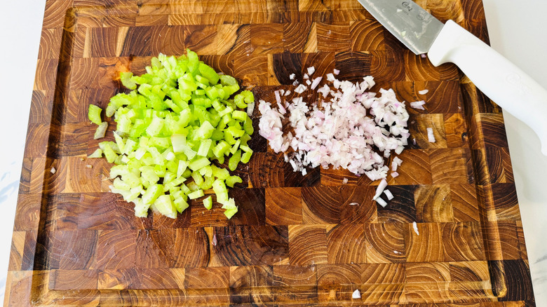 Sliced celery and shallot on wooden board