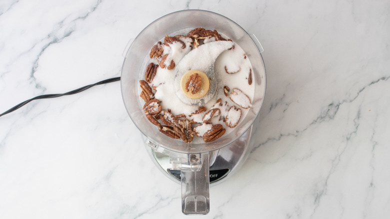 Pecan halves and granulated sugar in a food processor
