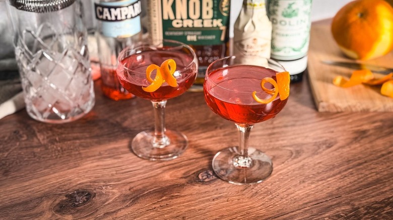 Old Pal cocktails on countertop with liquor bottles and orange