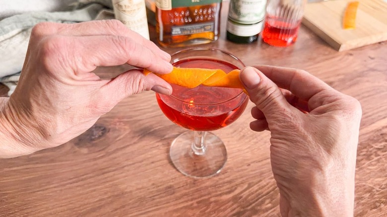 Twisting orange peel over Old Pal cocktail