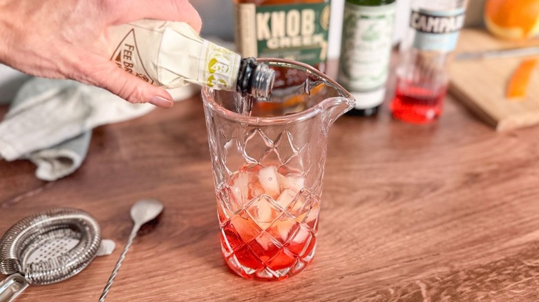 Adding cardamom bitters to Old Pal cocktail in crystal mixing pitcher