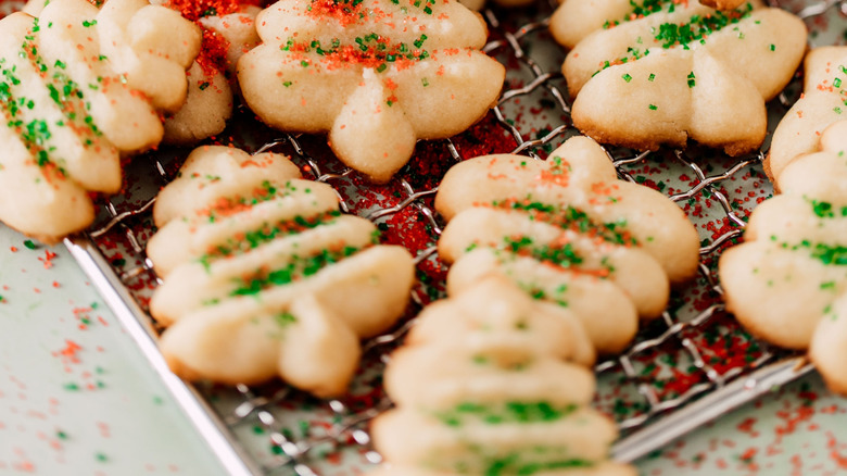 Festive spritz cookies decorated with sprinkles on drying rack.