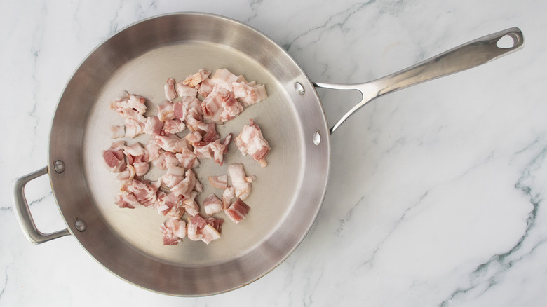 Raw diced bacon in a stainless skillet