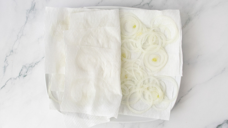 Raw onions on a large plate with paper towels
