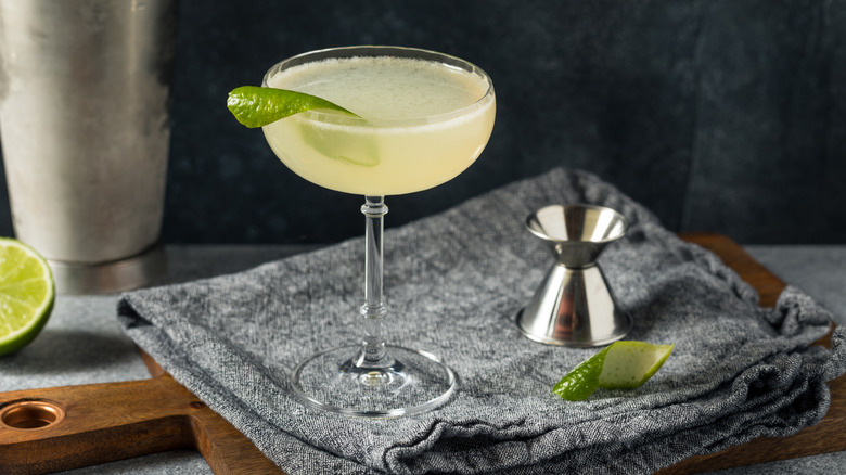 A Gimlet cocktail garnished with a lime peel