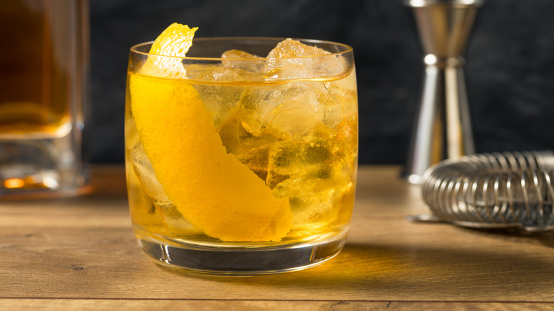 A Rusty Nail cocktail in a glass garnished with lemon peel