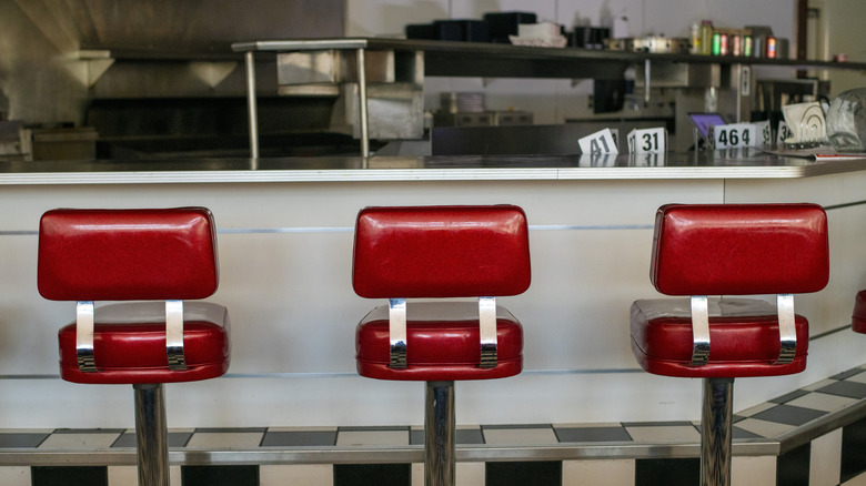 Burgundy leather and chrome swivel stools at a white diner counter