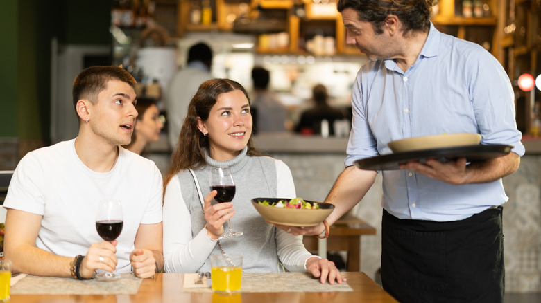 Waiter serving a meal to a woman at a restaurant