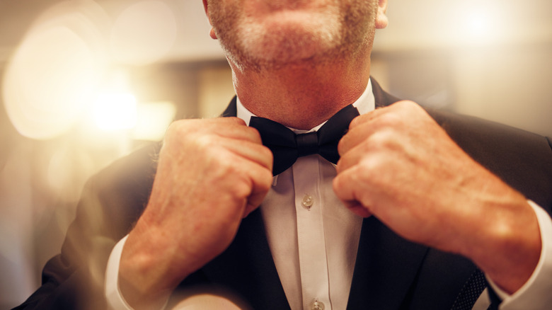 Man adjusting bowtie of formal tuxedo