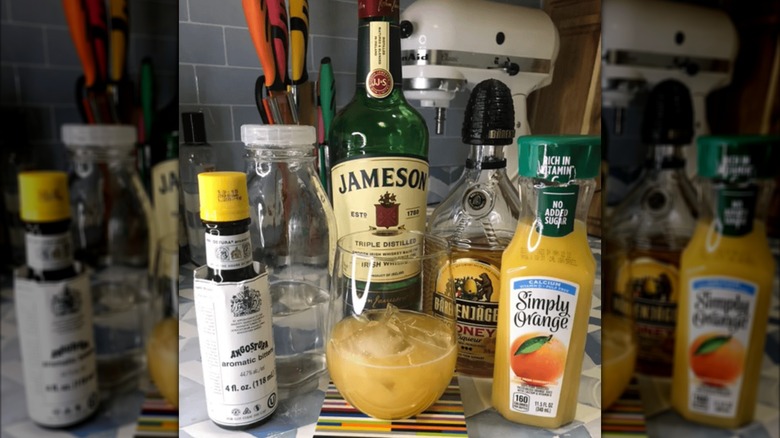 Woman's hand pouring a Friskey Whiskey cocktail into a glass with ice on counter.