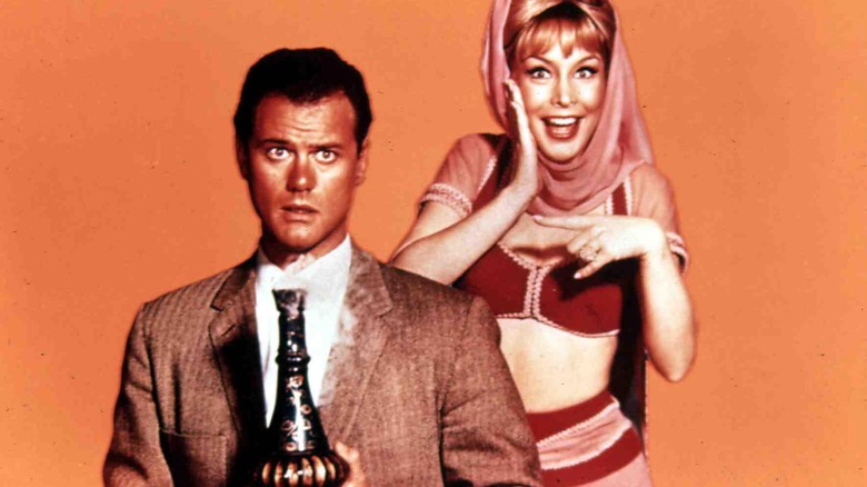 Actor Larry Hagman holding bottle with Barbra Eden dressed as Jeannie next to him